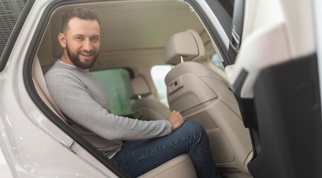 middle-aged man examining the back of a new car.