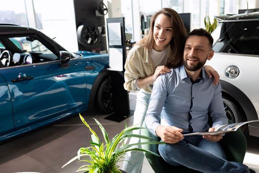 a married couple studying the terms of new car insurance at a car dealership. Concept of road safety