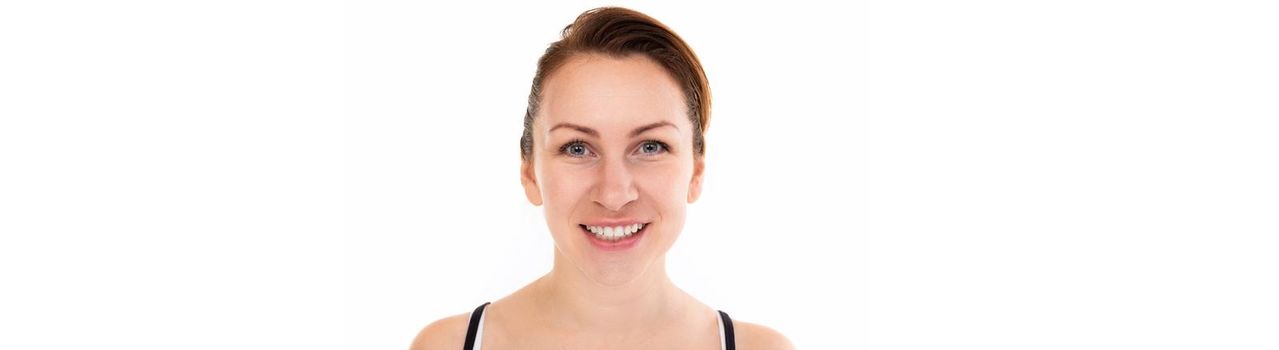 young woman with a smile with snow-white teeth looking at the camera on a white background.