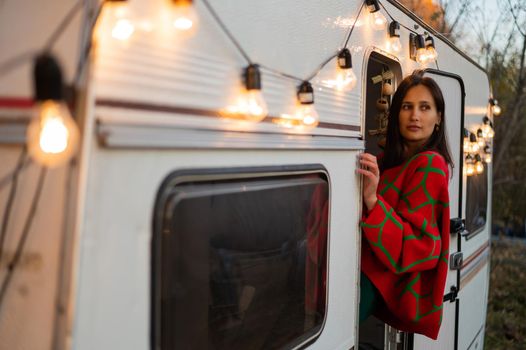 Caucasian woman in oversized red knitted jumper travels in motorhome in autumn