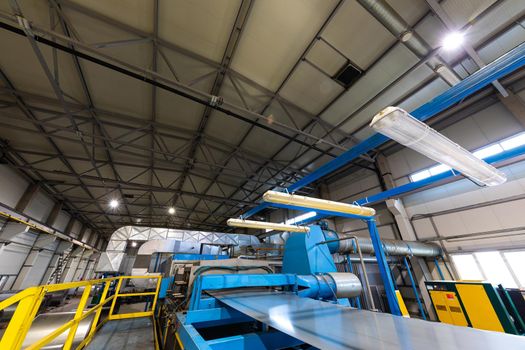 Production line of metal tile for roof. Steel forming machine in metalwork factory workshop. Metal sheet profiling machine.
