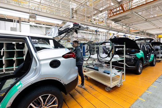 Minsk, Belarus - Dec 15, 2021: Car bodies are on assembly line. Factory for production of cars. Modern automotive industry. Electric car factory, conveyor.