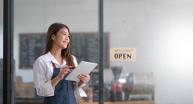 Startup successful small business owner sme beauty girl stand with tablet smartphone in coffee shop restaurant. Portrait of asian tan woman barista cafe owner. SME entrepreneur seller business concept.