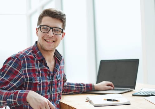 Young man with glasses working on his notebook, early in the morning, getting the business out of the way nice and early in the day