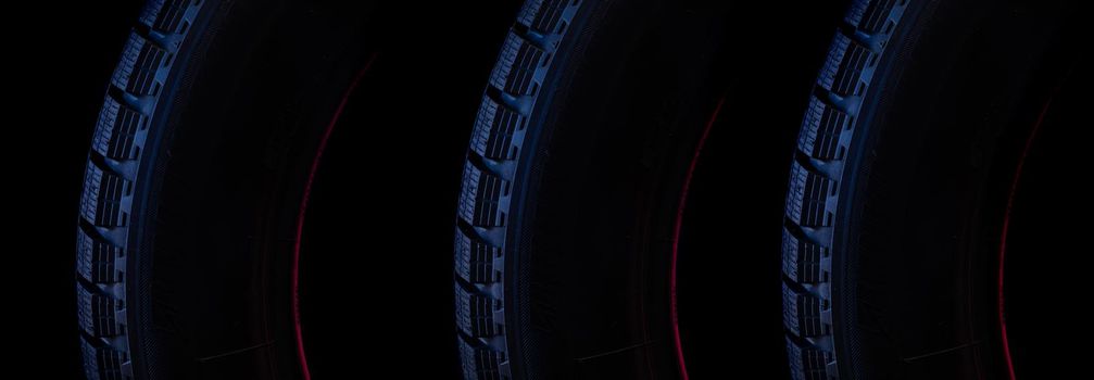 part of the tread of a winter tire on a black background close-up with blue backlight.