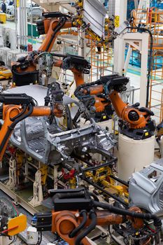 Vertical photo of automobile production line. Modern car assembly plant. Auto industry. Interior of a high-tech factory, modern production.