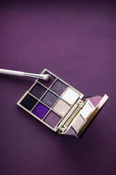 Cosmetic branding, mua and girly concept - Eyeshadow palette and make-up brush on purple background, eye shadows cosmetics product as luxury beauty brand promotion and holiday fashion blog design