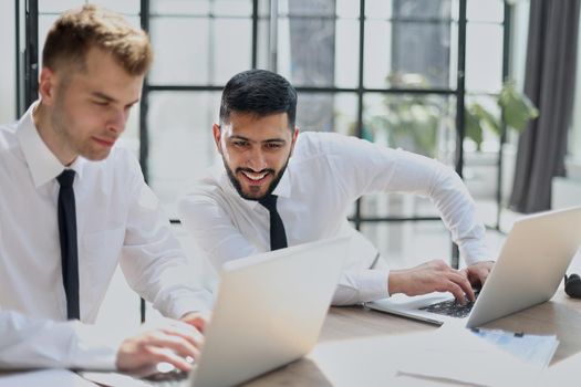 Discussing the problem. Two confident business man discussing something on the computer