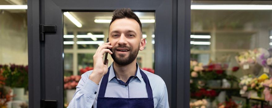 florist in the background fridge with fresh flowers takes an order by phone.