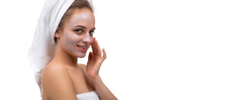 a woman after a shower applies a cream on her face.