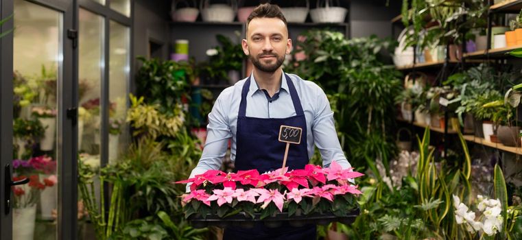 florist businessman with a tray of fresh flowers on the background of a flower shop.