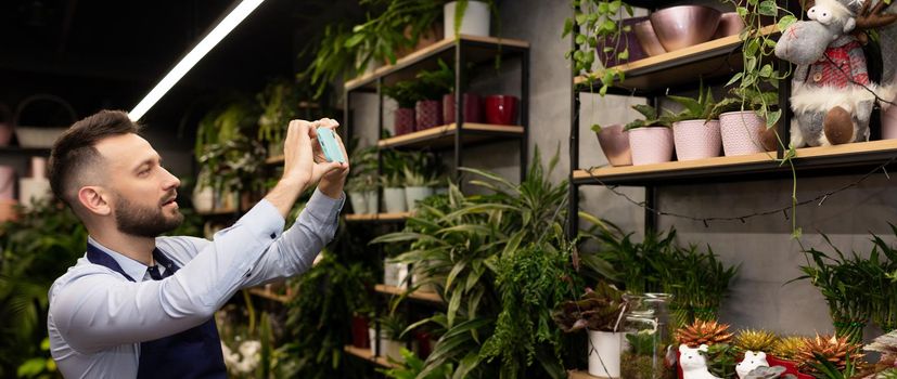 florist man takes pictures of potted plants and flowers in his bouquet shop.