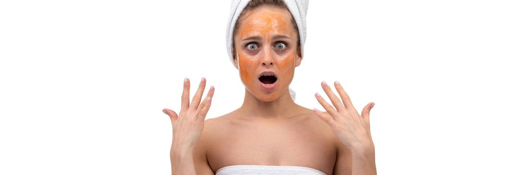 portrait of a woman after a shower with an orange cosmetic mask on her face that burns the skin.