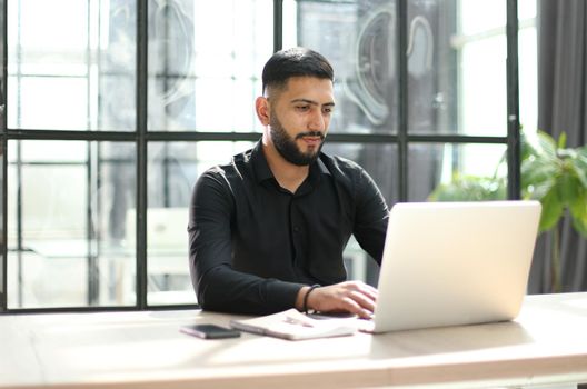 Man Working At Desk In Busy Creative Office