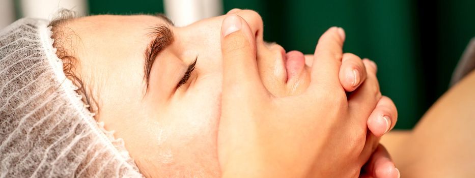 Face massage. Beautiful caucasian young white woman having a facial massage with closed eyes in a spa salon