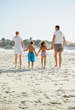 Its been a great day for them...A happy young family walking down the beach together in the sunshine