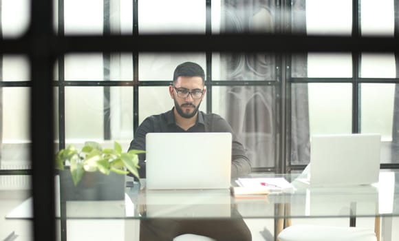 Businessman using his laptop, pc. Serious handsome bearded man worker laptop