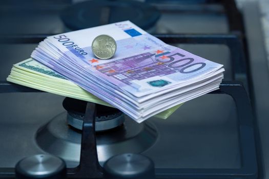 The Russian ruble stands on euro banknotes, near the gas burner of the home stove. The concept of gas payment in rubles