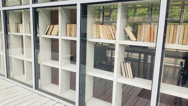 White shelving with books, behind glass, in summer. Copy space