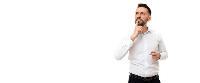 puzzled man chooses something with his finger to his lips with a pensive look on a white background