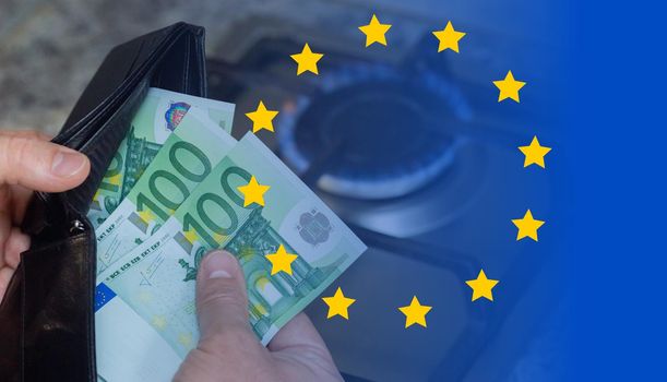 Mens hands with a purse and euro banknotes on the background of a gas stove. A concept showing the energy crisis in Europe. Rising prices and the inaccessibility of gas.
