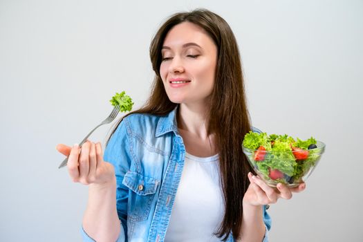 Beautiful young woman eats salad with lettuce, tomato and olives. Healthy lifestyle.