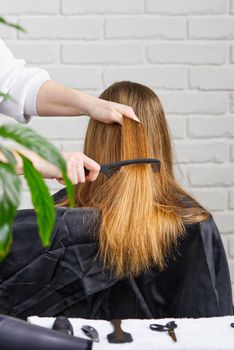 Beautiful girl with long hair. creating a hairstyle for a young unrecognizable girl. Hair styling process.