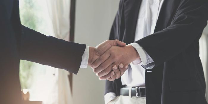 Two confident business man shaking hands during a meeting in the office, success, dealing, greeting and partner concept..