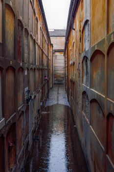 Unidentifiable cemetery wall burial mausoleum tombs under rain in Certosa Bologna, Italy.