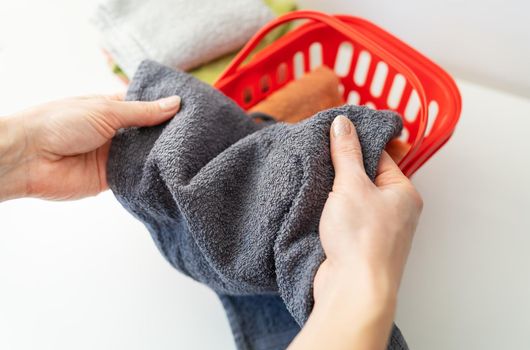 A woman's hand holds a terry towel from a clothes basket. Towel after washing. The concept of a clean and soft towel