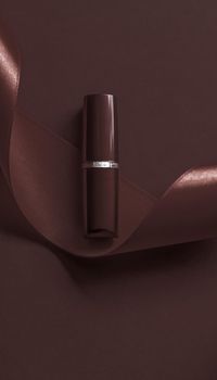 Cosmetic branding, glamour lip gloss and shopping sale concept - Luxury lipstick and silk ribbon on chocolate holiday background, make-up and cosmetics flatlay for beauty brand product design