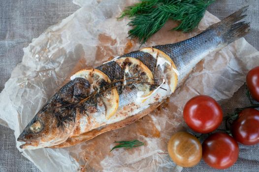 Appetizing sibas fish with greens and vegetables. On a wooden background.
