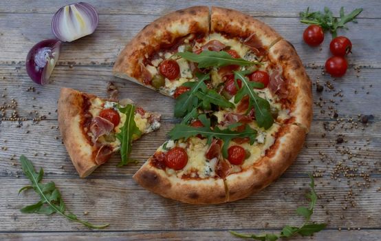 Pizza with cheese and tomato on wooden background with onion. One slice of pizza is taken out. High quality photo