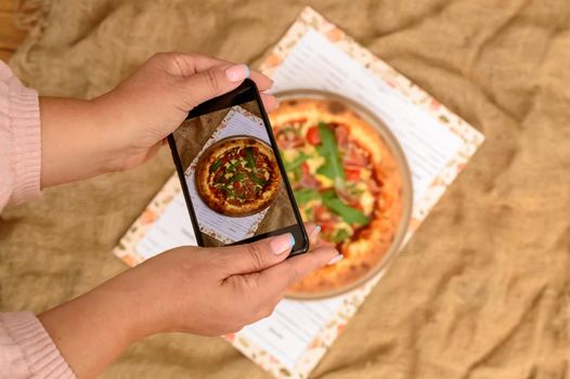 Photographing food. Hands taking picture of delicious pizza with smartphone. High quality photo
