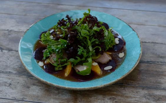 Salad with pulled duck, almond nuts and orange on a wooden background. High quality photo