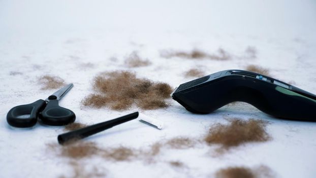 close up of Barber tools and a lot of cut hair from the body, on white background. tools for depilation, hair removal, Men's haircut. clipper, electric razor, trimer, scissors. High quality photo