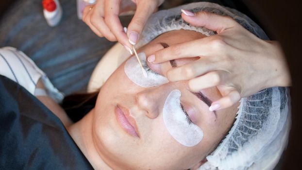 beauty saloon. close-up, procedure for eyelash extension. the master wipes the eyelashes to the client with a cotton swab soaked in antiseptic, prepares the client for the procedure. High quality photo