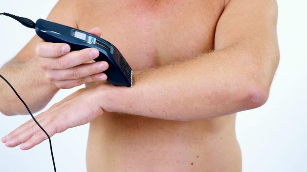 Close-up of a very hairy Man haircut body hair on his whole body, hands by himself with a clipper, electric razor, trimer. isolated on white background. Naked man shaves his body. High quality photo