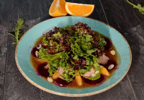 Salad with pulled duck, almond nuts and orange on a wooden background. High quality photo