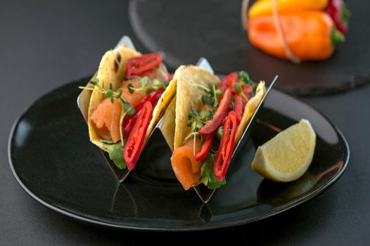 Spicy tacos with tomatoes and meat on a dark background