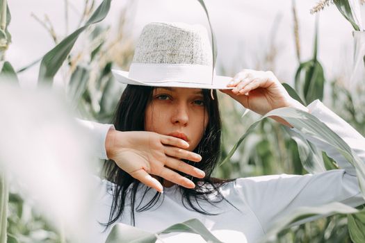 A brunette girl in a white dress in a cornfield. The concept of harvesting.