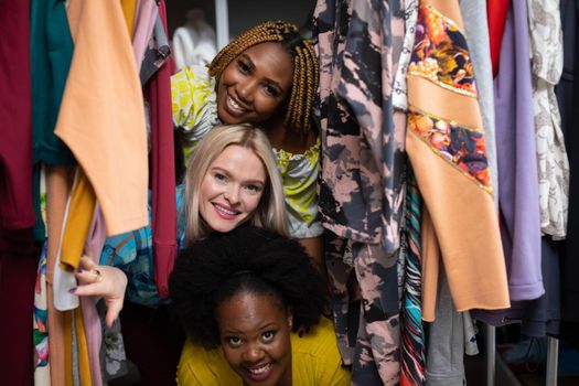 Three cheerful girls during exciting clothes shopping. Two dark-skinned women and one of Caucasian beauty. Lined up one above the other.