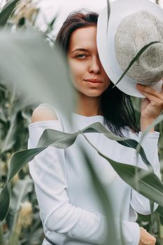 A brunette girl in a white dress in a cornfield. The concept of harvesting.