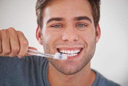 Keeping his teeth sparkly white. a man brushing his teeth
