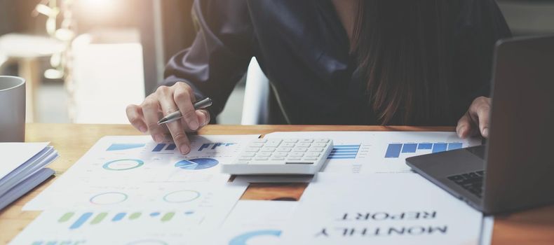 Cropped image of woman hand using calculator, working with graph chart and analyzing business strategy, financial statistic, sitting at desk office, vertical view..