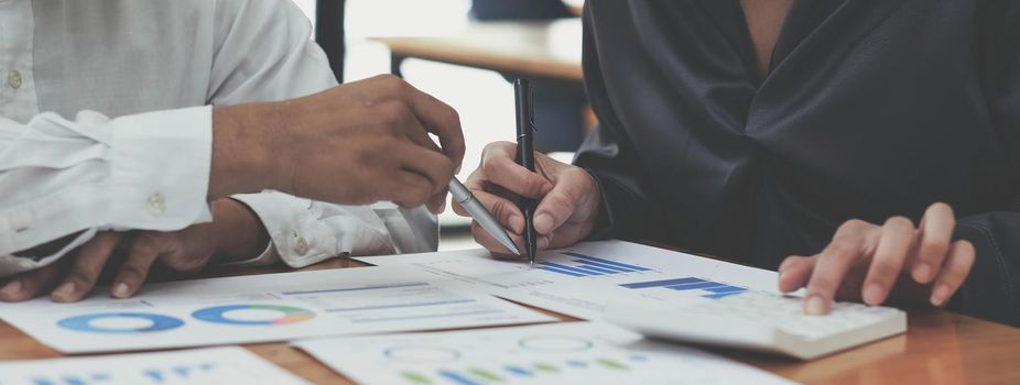 Cropped shot of business people hands holding pen and discussing about business plan, using computer and business graph, analyzing or calculating business results..