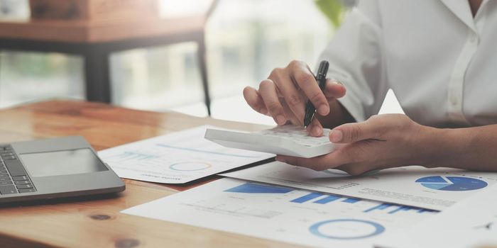 woman hand using calculator, working with graph chart and analyzing business strategy, financial statistic, sitting at desk office