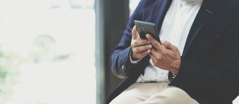 Close up hand of businessman using smartphone at coffee shop cafe.