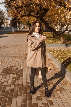 A stylish brunette woman walks around the autumn city. The season is autumn.