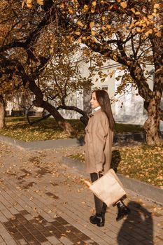 A stylish brunette woman walks around the autumn city. The season is autumn.